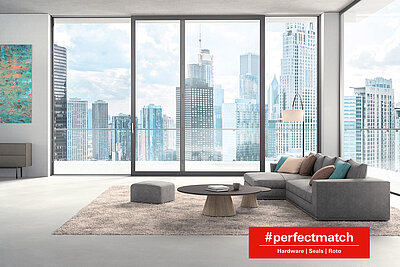 Interior view of a living room with Roto sliding system in a high-rise building with a view of surrounding high-rise buildings. The Perfect Match label 'Hardware | Seals | Roto' is located at the bottom right.